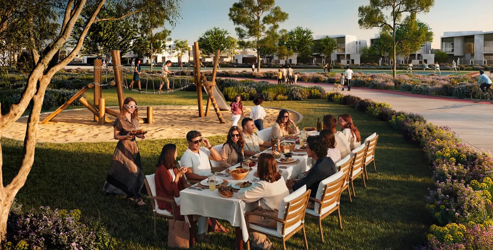 Developer rendering of a family dinner under trees in a Talay garden with villas beyond